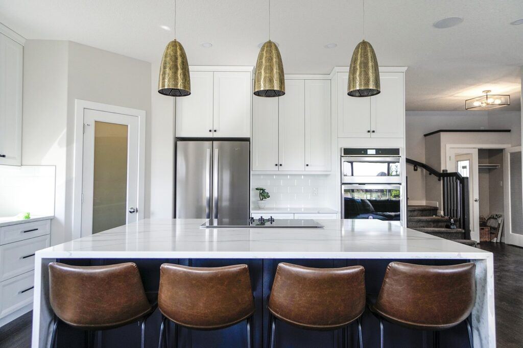 White colored kitchen with brown bar stools at the center Island.